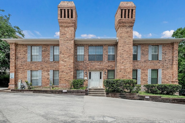view of front facade featuring a chimney and brick siding