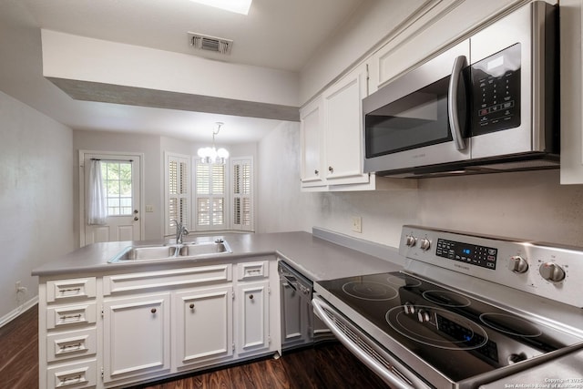 kitchen featuring stainless steel microwave, electric range, a sink, visible vents, and a peninsula