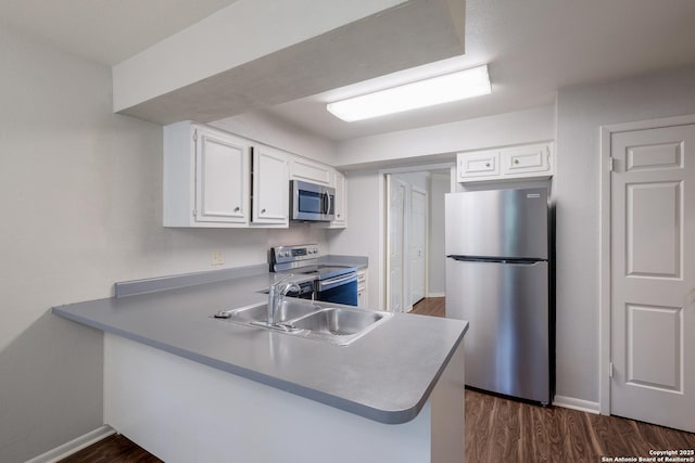 kitchen with dark wood-style floors, stainless steel appliances, white cabinetry, and a sink