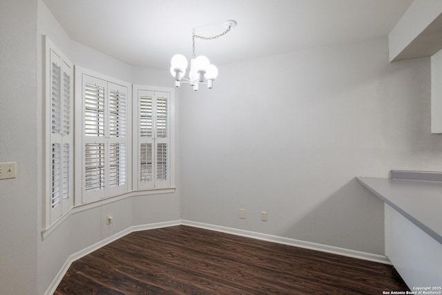 unfurnished dining area featuring baseboards, wood finished floors, and a notable chandelier
