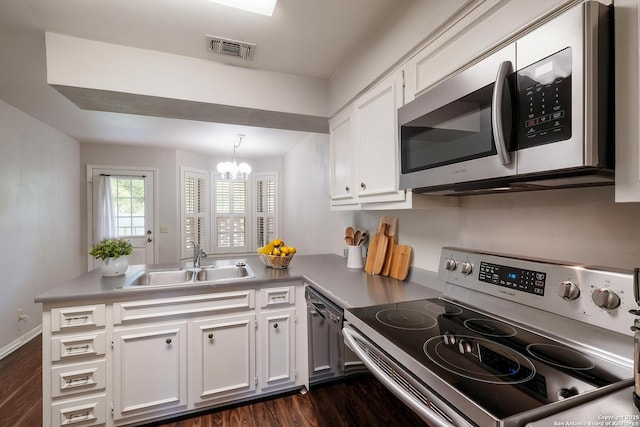 kitchen featuring stainless steel microwave, a sink, visible vents, range with electric stovetop, and a peninsula