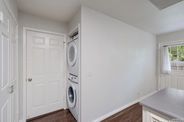 washroom with dark wood-style floors, stacked washing maching and dryer, laundry area, and baseboards