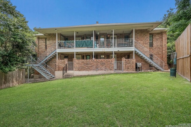 rear view of property featuring a lawn, stairway, and brick siding