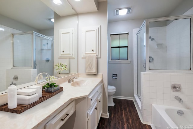 bathroom featuring wood finished floors, toilet, a bathtub, vanity, and a stall shower