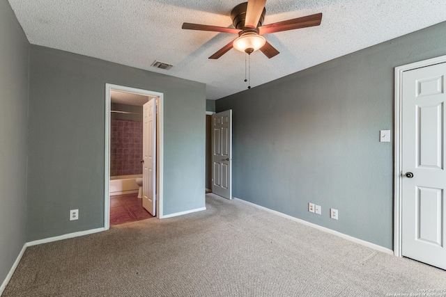 unfurnished bedroom with a textured ceiling, carpet flooring, visible vents, ensuite bathroom, and baseboards