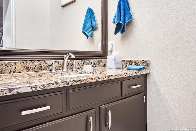 bathroom with a textured wall and vanity