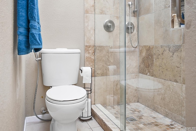 full bathroom featuring tile patterned floors, a textured wall, a stall shower, and toilet