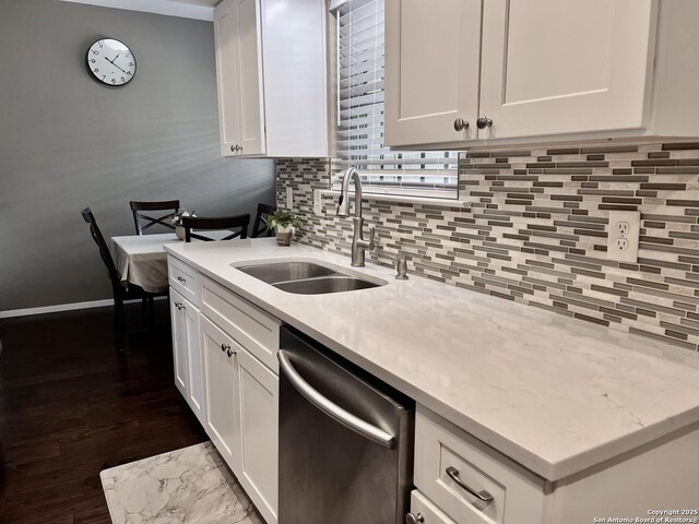 kitchen featuring stainless steel dishwasher, a sink, white cabinetry, and backsplash
