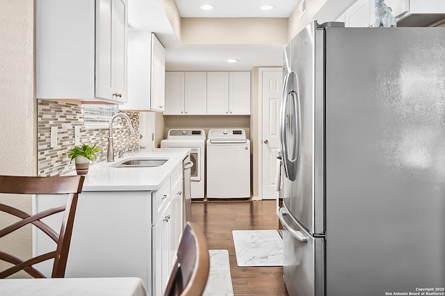 clothes washing area with laundry area, dark wood-style flooring, a sink, recessed lighting, and washer and dryer