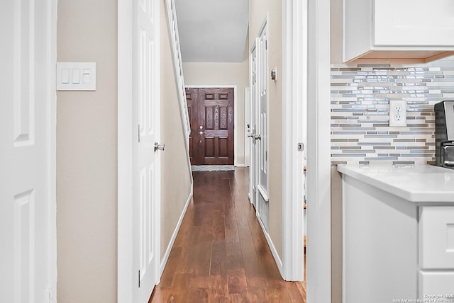 corridor featuring baseboards and dark wood-type flooring
