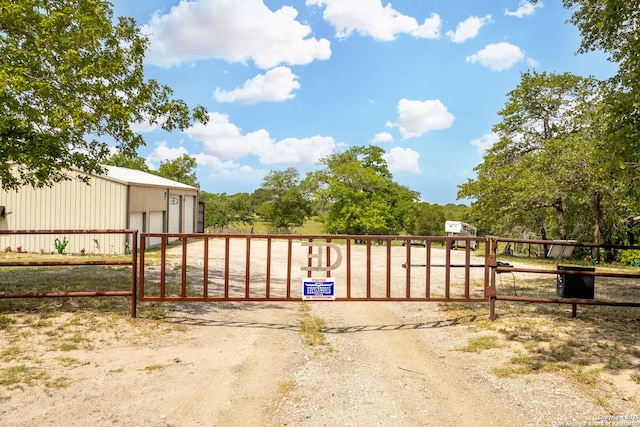 view of gate with a pole building, an outbuilding, and fence
