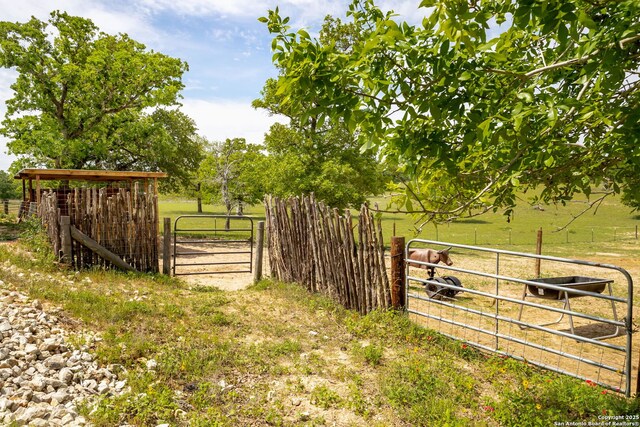 view of gate featuring a rural view and fence