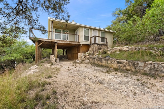 view of front facade with a carport, dirt driveway, and a wooden deck