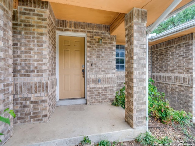 property entrance featuring brick siding and a porch