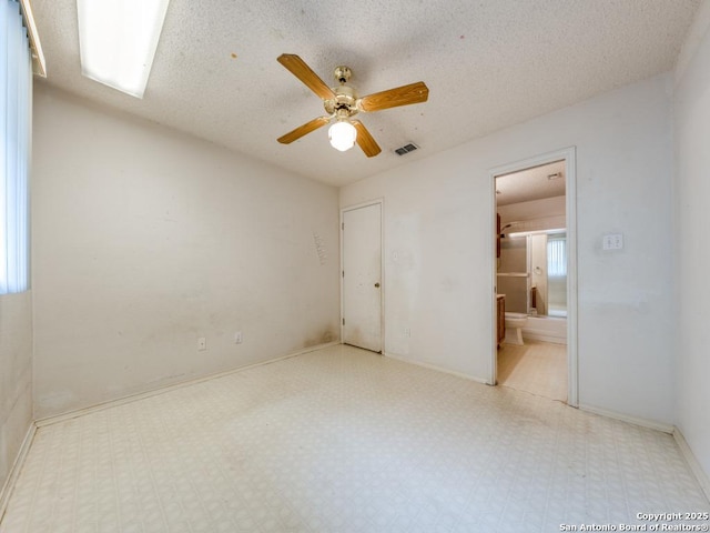 unfurnished bedroom featuring tile patterned floors, visible vents, ensuite bathroom, and baseboards