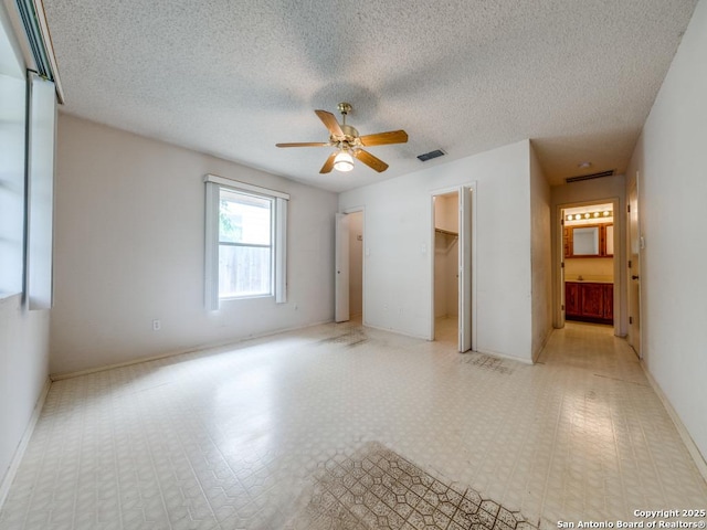 8434 Timber Loche, San Antonio, TX 78250 - unfurnished bedroom featuring a walk in closet, a ceiling fan, a textured ceiling, ensuite bathroom, and baseboards