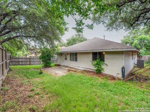 back of house featuring central AC, a fenced backyard, a lawn, and a patio area