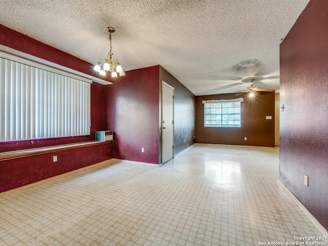 unfurnished room featuring a textured ceiling, baseboards, and ceiling fan with notable chandelier