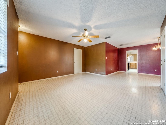 unfurnished room featuring baseboards, visible vents, a ceiling fan, and a textured ceiling