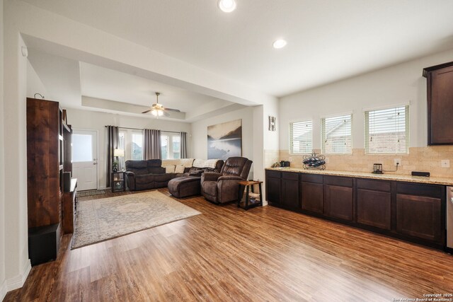 living room with recessed lighting, ceiling fan, light wood-style flooring, and a raised ceiling