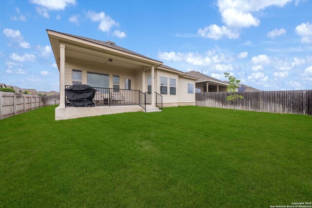 rear view of property with a yard, a fenced backyard, and a patio area