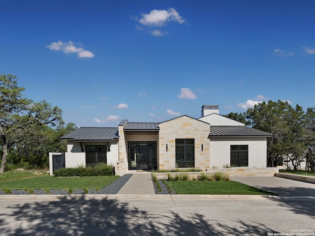 modern home with metal roof, a standing seam roof, and stone siding