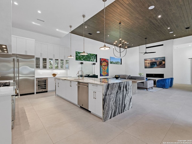 kitchen with white cabinets, a sink, beverage cooler, high quality appliances, and a high ceiling