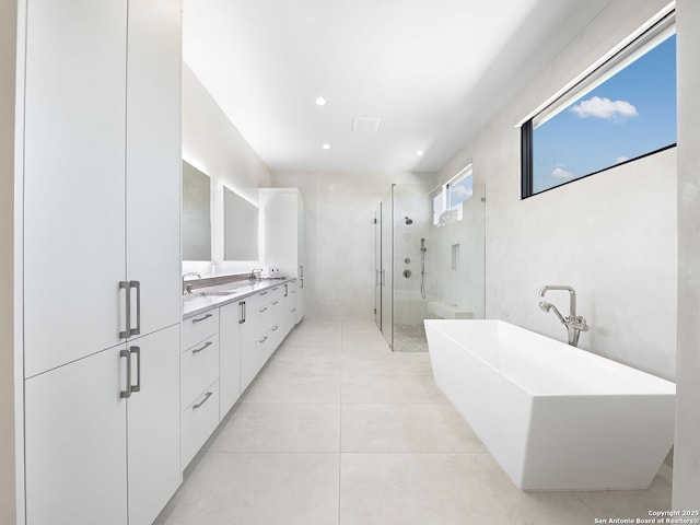 bathroom with a sink, tile patterned floors, a stall shower, double vanity, and a freestanding bath