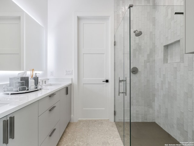 full bathroom with a stall shower, double vanity, and a sink