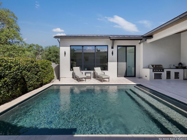 back of house featuring an outdoor kitchen, a patio area, stucco siding, and an outdoor pool