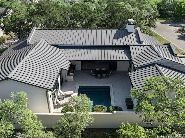 rear view of property featuring a patio, a chimney, metal roof, a standing seam roof, and fence private yard