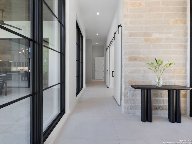 hall with a barn door, recessed lighting, and tile patterned flooring