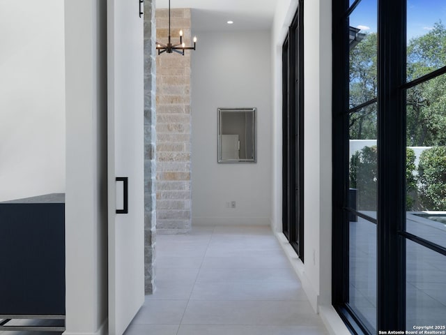 hall featuring tile patterned flooring, a chandelier, and baseboards