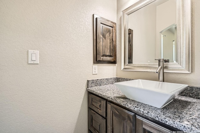 bathroom with a textured wall and vanity