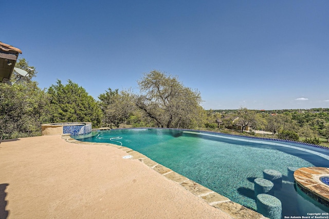 view of pool featuring a pool with connected hot tub and a patio area