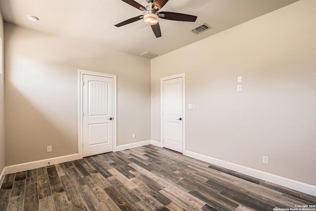 empty room featuring dark wood finished floors, visible vents, a ceiling fan, and baseboards