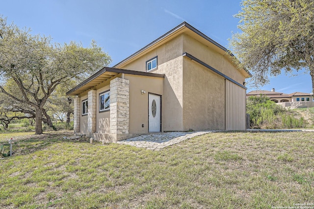 back of house featuring a yard and stucco siding