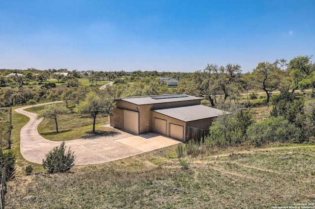 exterior space featuring a standing seam roof, metal roof, a garage, roof mounted solar panels, and driveway