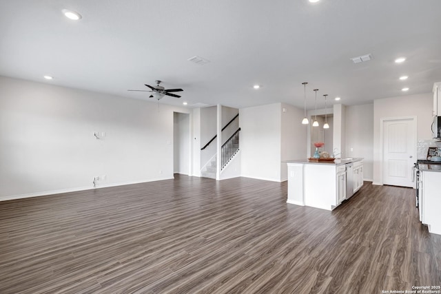 9416 Tennant Ln, Converse, TX 78109 - unfurnished living room featuring baseboards, stairs, ceiling fan, dark wood-style floors, and visible vents