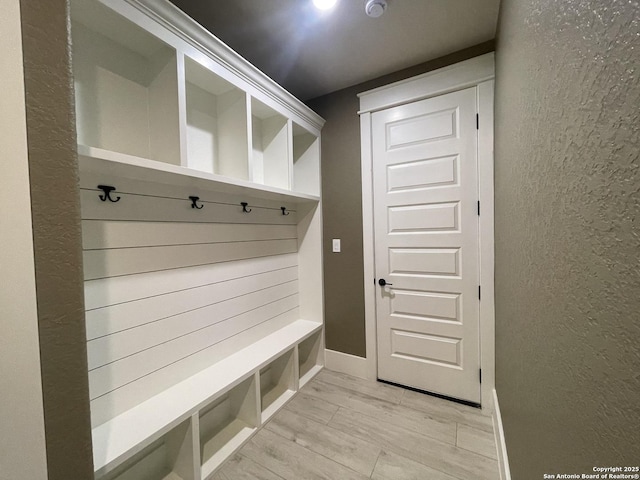 mudroom featuring a textured wall and baseboards