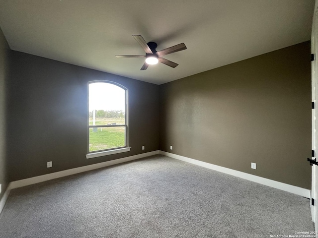 carpeted spare room with baseboards and a ceiling fan
