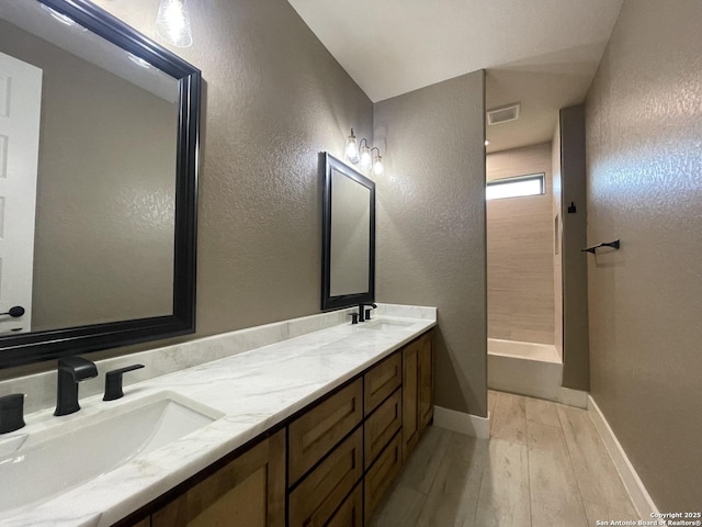 full bathroom featuring walk in shower, a sink, wood finished floors, and visible vents