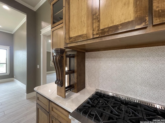 interior details with glass insert cabinets, light countertops, ornamental molding, baseboards, and light wood-type flooring
