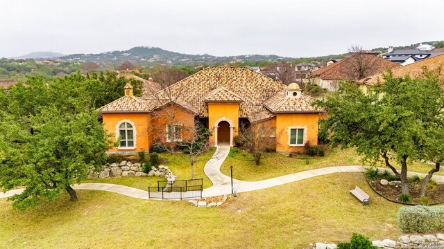 mediterranean / spanish house featuring a front yard, stucco siding, and a mountain view