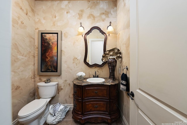 half bath featuring toilet, wallpapered walls, vanity, and baseboards