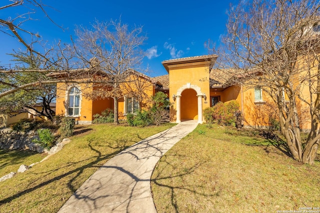 mediterranean / spanish-style home with stucco siding, a tiled roof, and a front yard