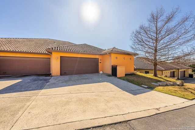 view of front of house with stucco siding, concrete driveway, and a tile roof