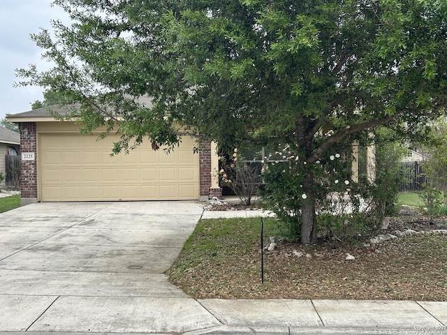 view of property hidden behind natural elements with driveway, an attached garage, and brick siding
