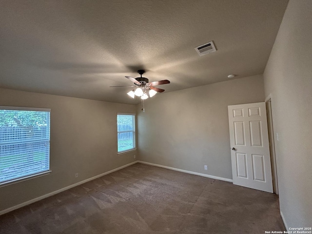 carpeted empty room featuring a textured ceiling, visible vents, ceiling fan, and baseboards