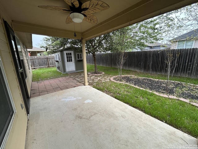 view of patio / terrace with a fenced backyard, a storage unit, ceiling fan, and an outbuilding
